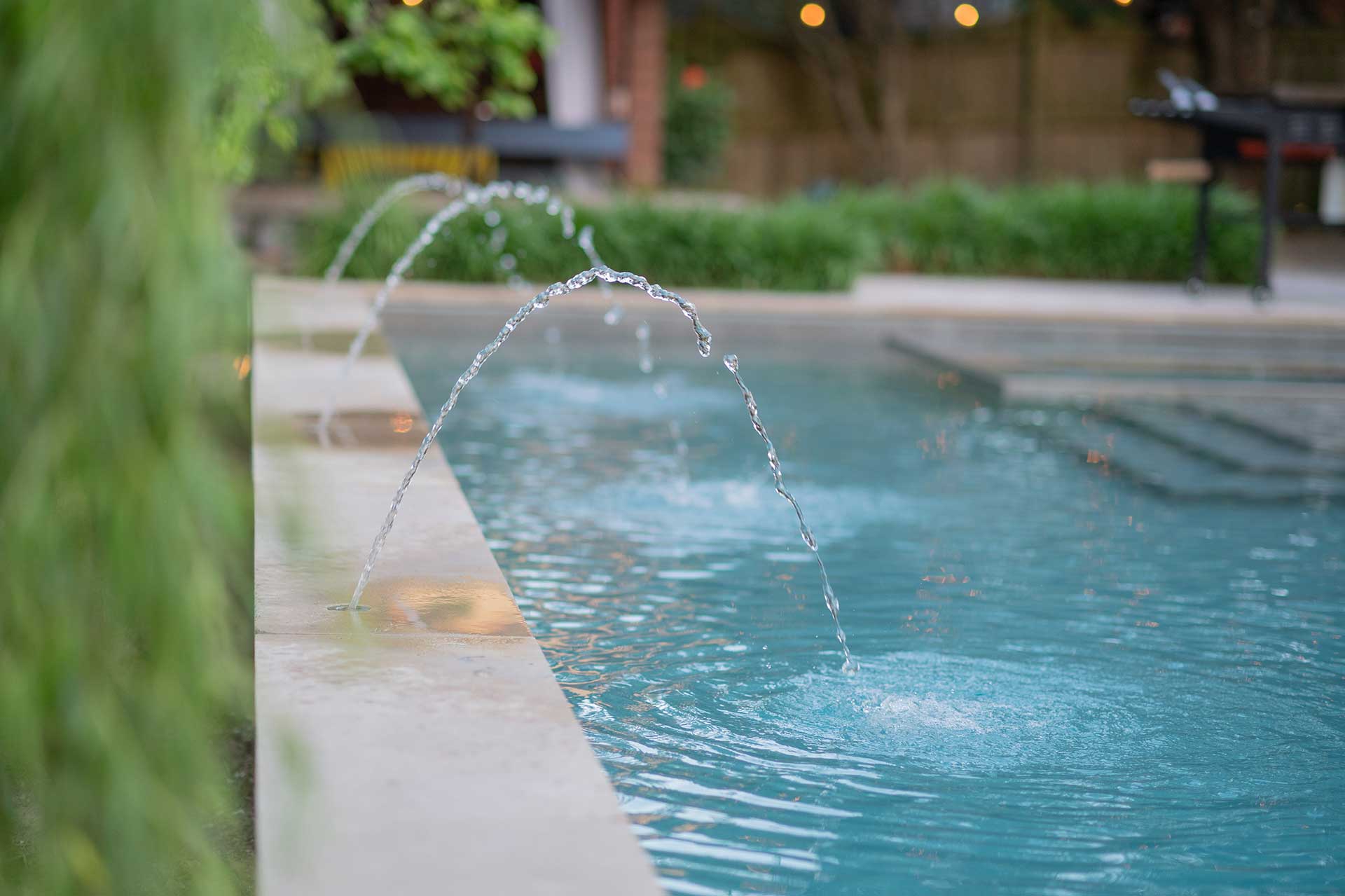 A pool with multiple waters streams coming from fountains landing in the water